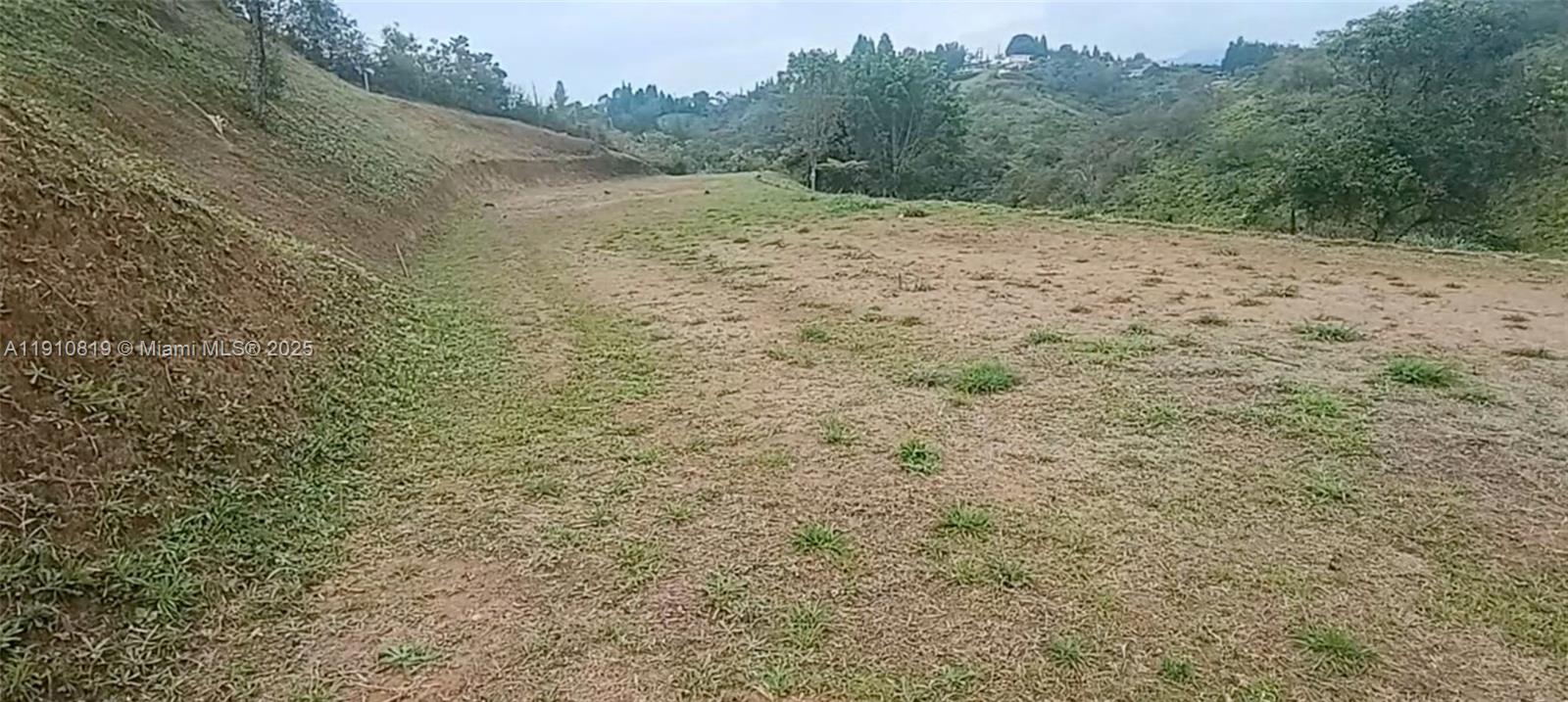 A wide, grassy, sloped plot of land overlooks a valley with distant trees and hills — Vereda Mampuesto Sector Garrido #6, C Colombia, C