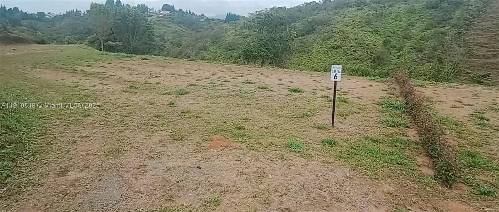 A vacant, grassy lot marked with a sign labeled Lote 6 in a hilly landscape — Vereda Mampuesto Sector Garrido #6, C Colombia, C