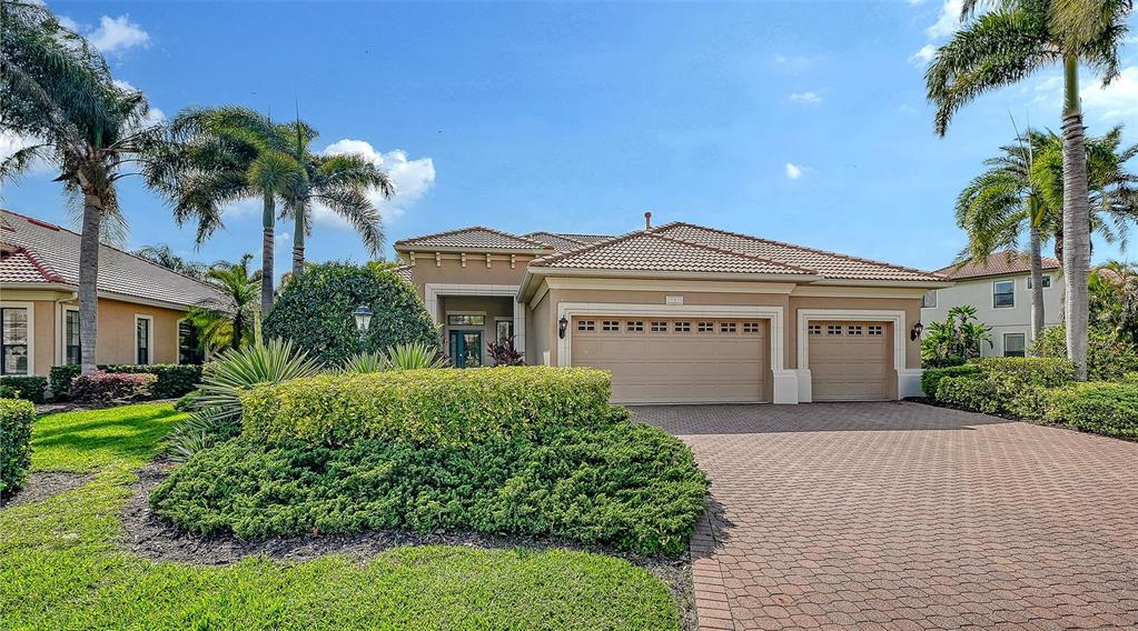 A single-story house with a tiled roof, three-car garage, and a paved driveway — 13911 SIENA LOOP, LAKEWOOD RANCH, FL