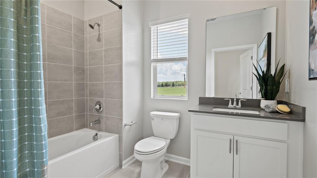 A bathroom features a tiled shower-tub combo, a white vanity, and a window with blinds — 4318 ST THOMAS WAY, KISSIMMEE, FL