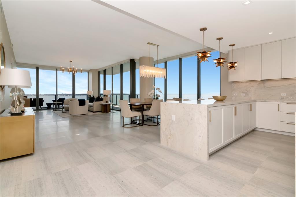 An open-concept kitchen and living area features light tile floors, white cabinetry, and floor-to-ceiling windows — 3101 W BAYSHORE BOULEVARD UNIT 804, TAMPA, FL