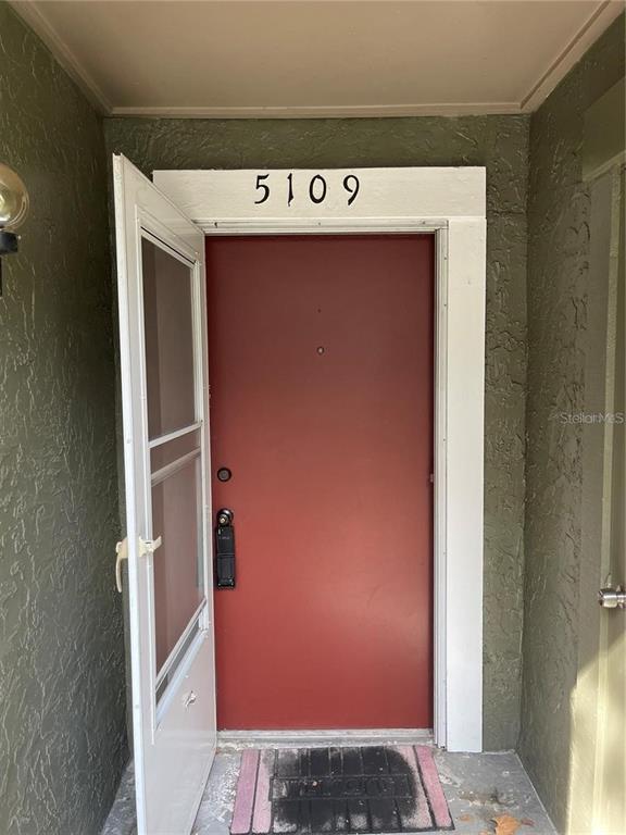 A red front door with a white storm door and the number 5109 above it — 5109 EAGLESMERE DRIVE UNIT 11A, ORLANDO, FL