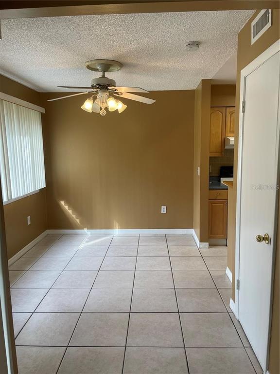 A dining area features tan walls, light-colored tile flooring, a ceiling fan, and vertical blinds — 5109 EAGLESMERE DRIVE UNIT 11A, ORLANDO, FL