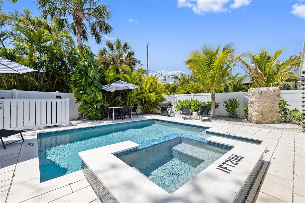 A backyard swimming pool and spa area surrounded by palm trees and a white fence — 3014 GULF DRIVE, HOLMES BEACH, FL