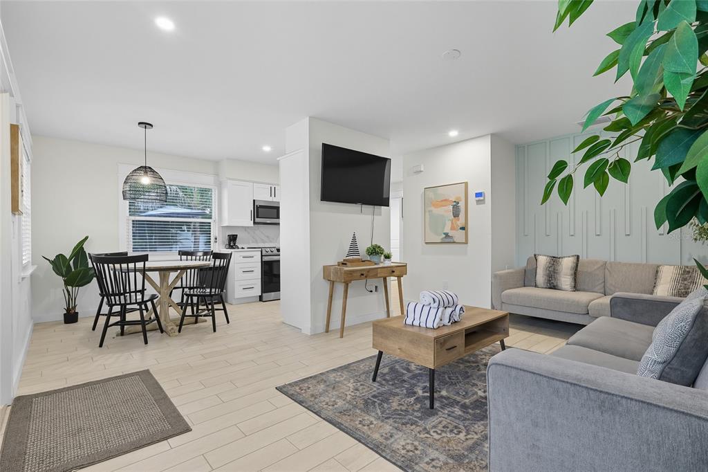 An open-concept living and dining area features light tile flooring, white cabinetry, and gray furniture — 3014 GULF DRIVE, HOLMES BEACH, FL