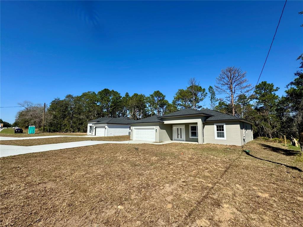 Two newly constructed single-story houses with attached garages sit on a grassy lot — 2085 W HAMPSHIRE BOULEVARD, CITRUS SPRINGS, FL