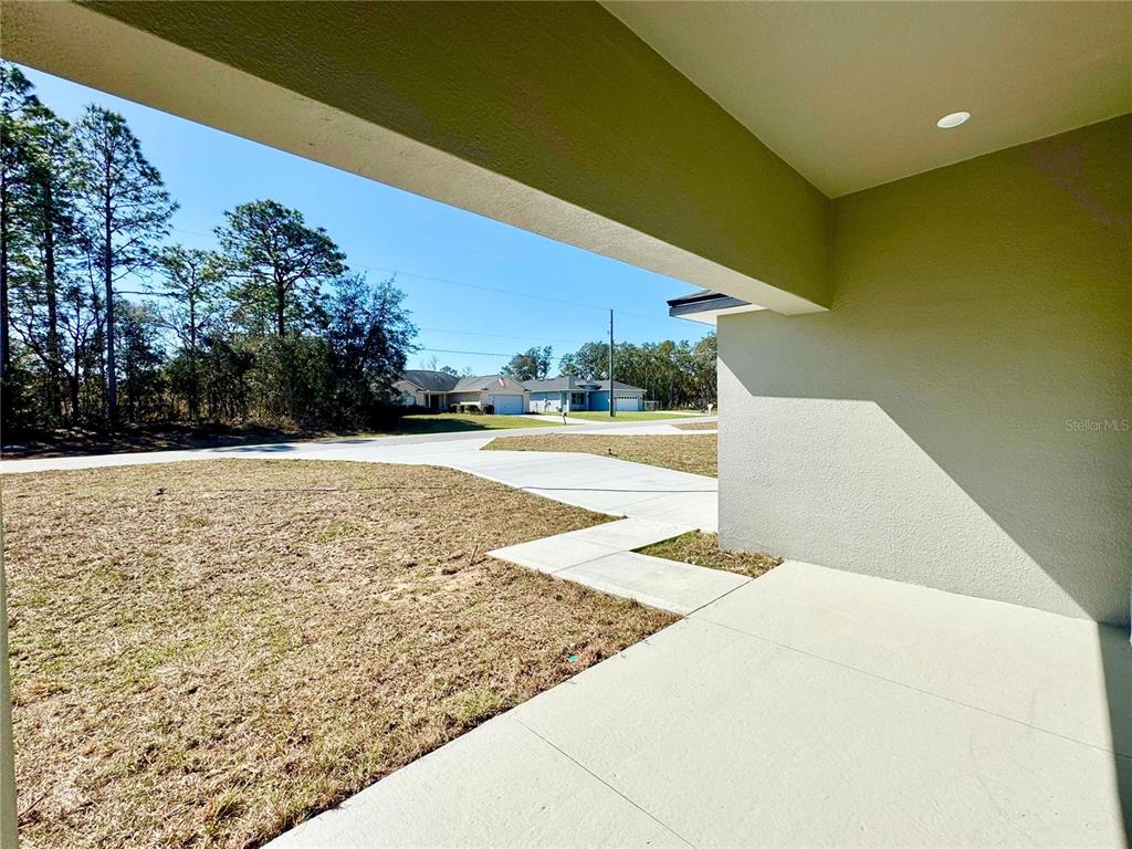 A view from a covered concrete porch looking out toward a suburban street and lawn — 2085 W HAMPSHIRE BOULEVARD, CITRUS SPRINGS, FL