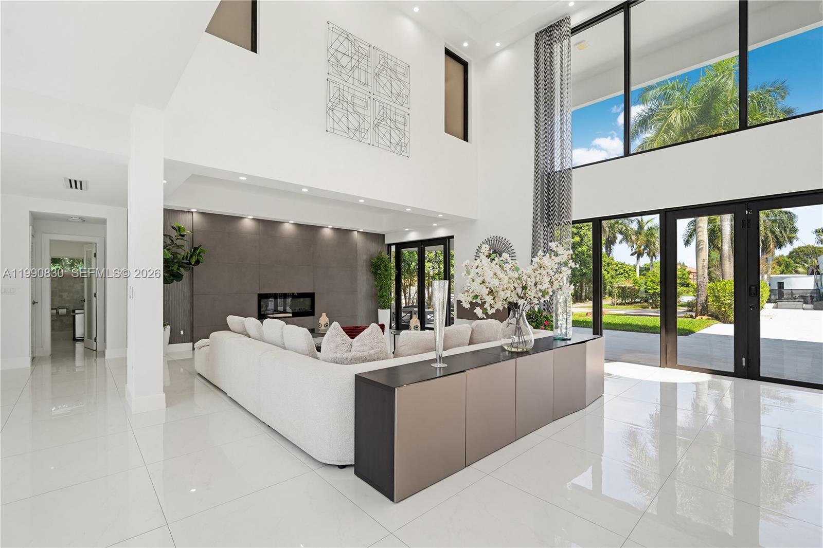 A modern living room features high ceilings, white tile floors, and a large sectional sofa — 14401 Sunset Ln, Southwest Ranches FL 33330, SOUTHWEST RANCHES, FL