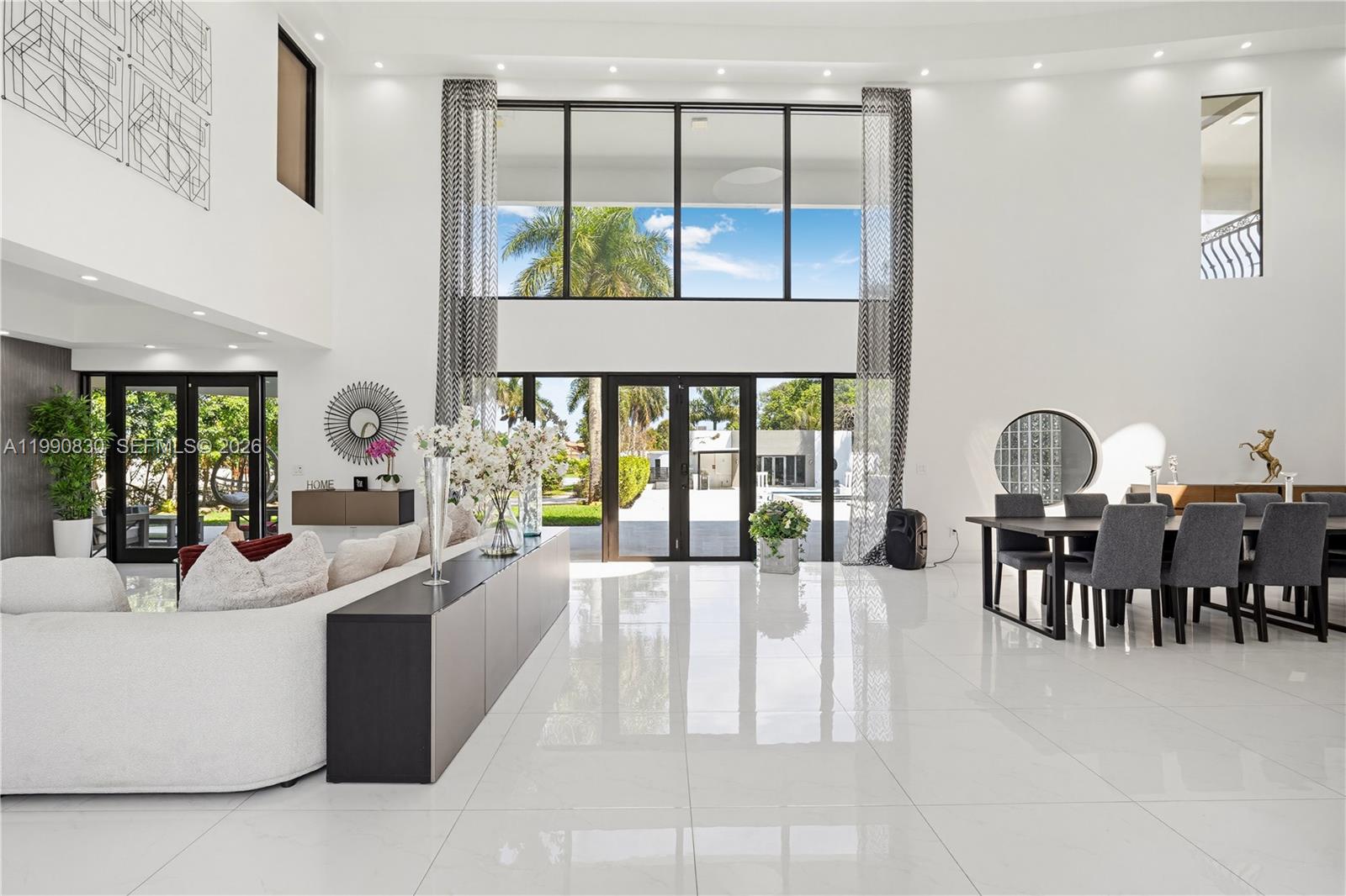 A spacious, high-ceilinged living and dining area features white tile floors and large glass doors — 14401 Sunset Ln, Southwest Ranches FL 33330, SOUTHWEST RANCHES, FL