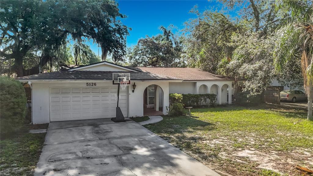 A single-story house with a white stucco exterior, a two-car garage, and a basketball hoop — 5126 ROLLING HILLS COURT, TAMPA, FL