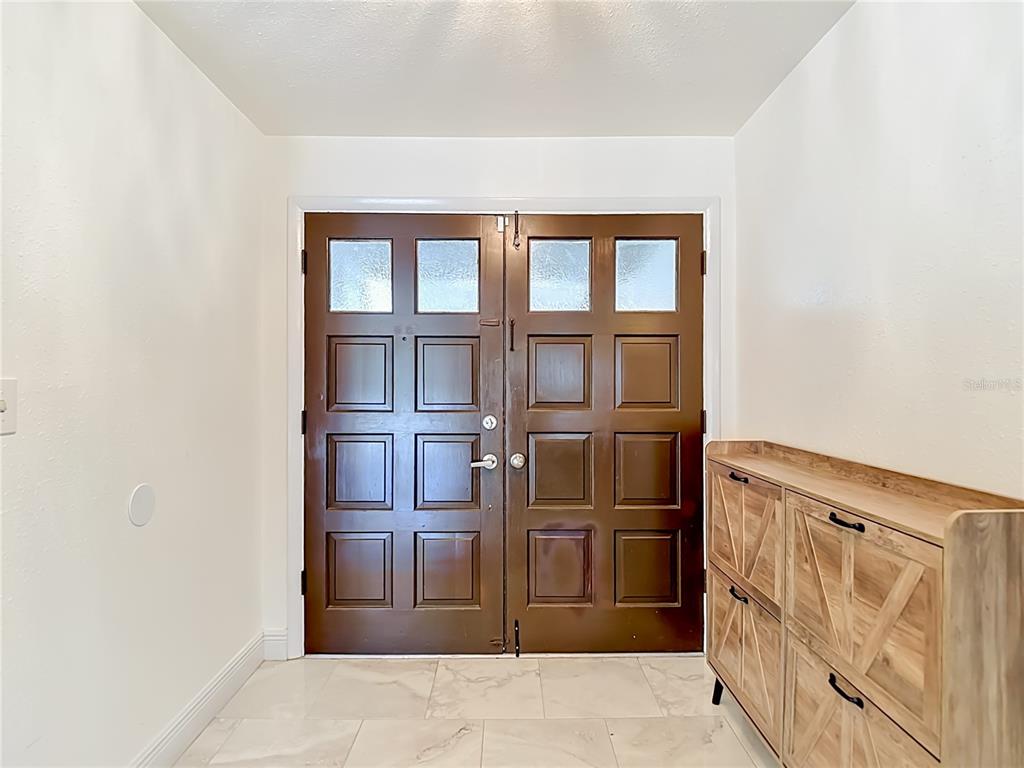 An entryway features double brown paneled doors, white walls, and light-colored tile flooring — 5126 ROLLING HILLS COURT, TAMPA, FL