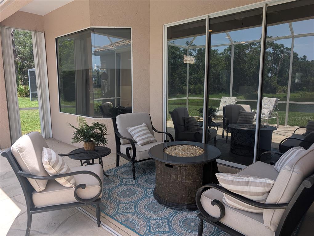A screened-in patio features outdoor furniture, a fire pit, and a patterned area rug — 4406 REFLECTIONS PARKWAY, SARASOTA, FL