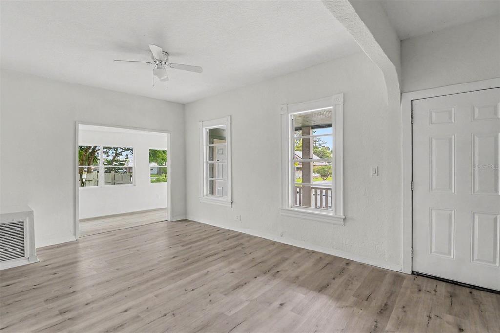 A bright living room features light wood-look flooring, white walls, and a ceiling fan — 1515 INDIANA AVENUE, ST CLOUD, FL