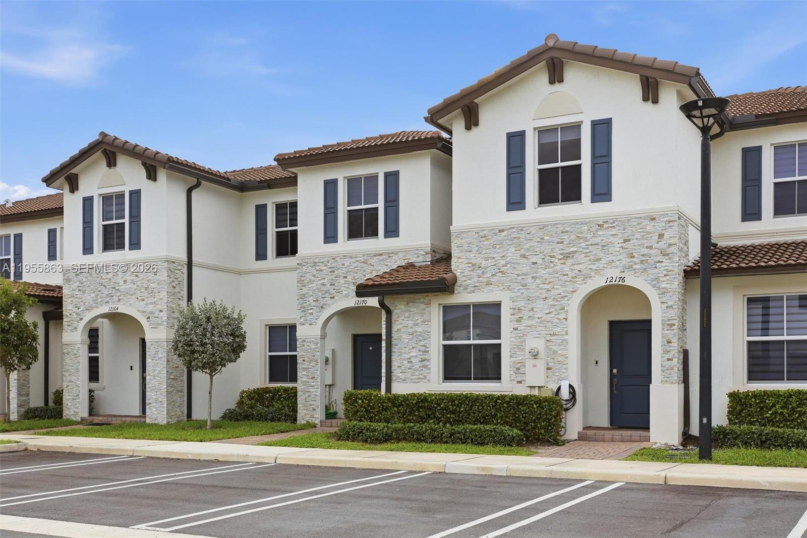 A row of three two-story townhouses features stucco walls, stone veneer accents, and tiled roofs — 12176 NW 23rd Path, Miami FL 33167, MIAMI, FL