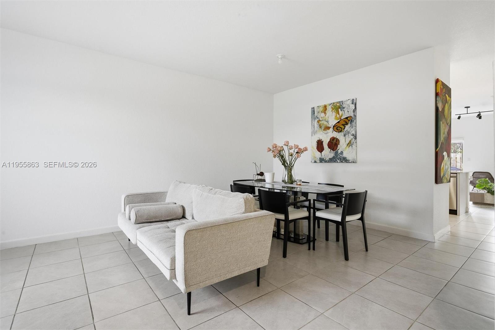 A living and dining area features a light-colored sofa, a glass dining table, and tile flooring — 12176 NW 23rd Path, Miami FL 33167, MIAMI, FL