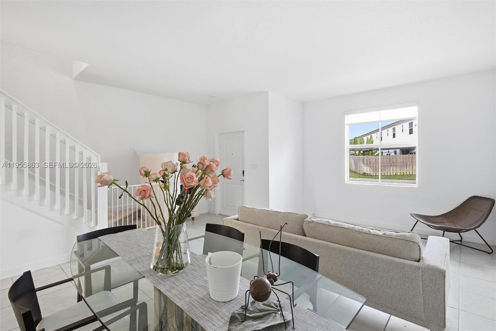 A dining area with a glass table and stairs leads into a living room — 12176 NW 23rd Path, Miami FL 33167, MIAMI, FL