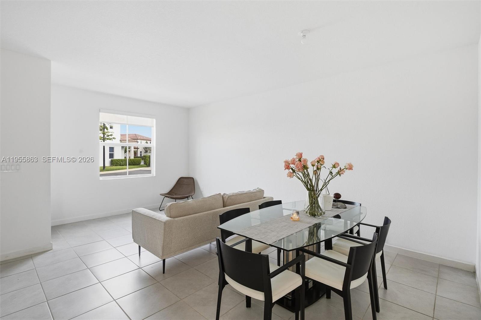 A dining area and living space feature white walls, tile floors, and a glass table — 12176 NW 23rd Path, Miami FL 33167, MIAMI, FL