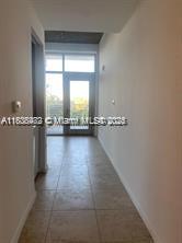 A hallway with light-colored tile flooring leads toward a glass door opening to a balcony — 3250 NE 1st Ave # 303, Miami FL 33137, MIAMI, FL