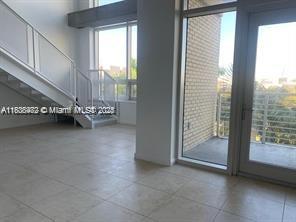 An interior view of a room with tile floors, a staircase, and a glass balcony door — 3250 NE 1st Ave # 303, Miami FL 33137, MIAMI, FL