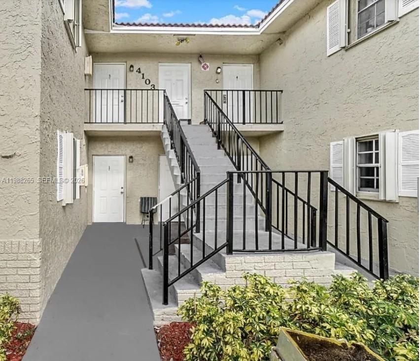 An exterior view of a two-story apartment building with a central staircase and metal railings — 4103 Riverside Dr, Coral Springs FL 33065, CORAL SPRINGS, FL