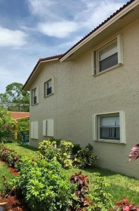 The exterior of a two-story tan stucco building features several windows and landscaping — 4103 Riverside Dr, Coral Springs FL 33065, CORAL SPRINGS, FL