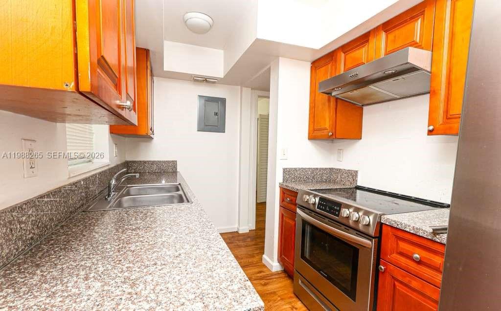 A galley kitchen features wood cabinets, granite countertops, and stainless steel appliances — 4103 Riverside Dr, Coral Springs FL 33065, CORAL SPRINGS, FL