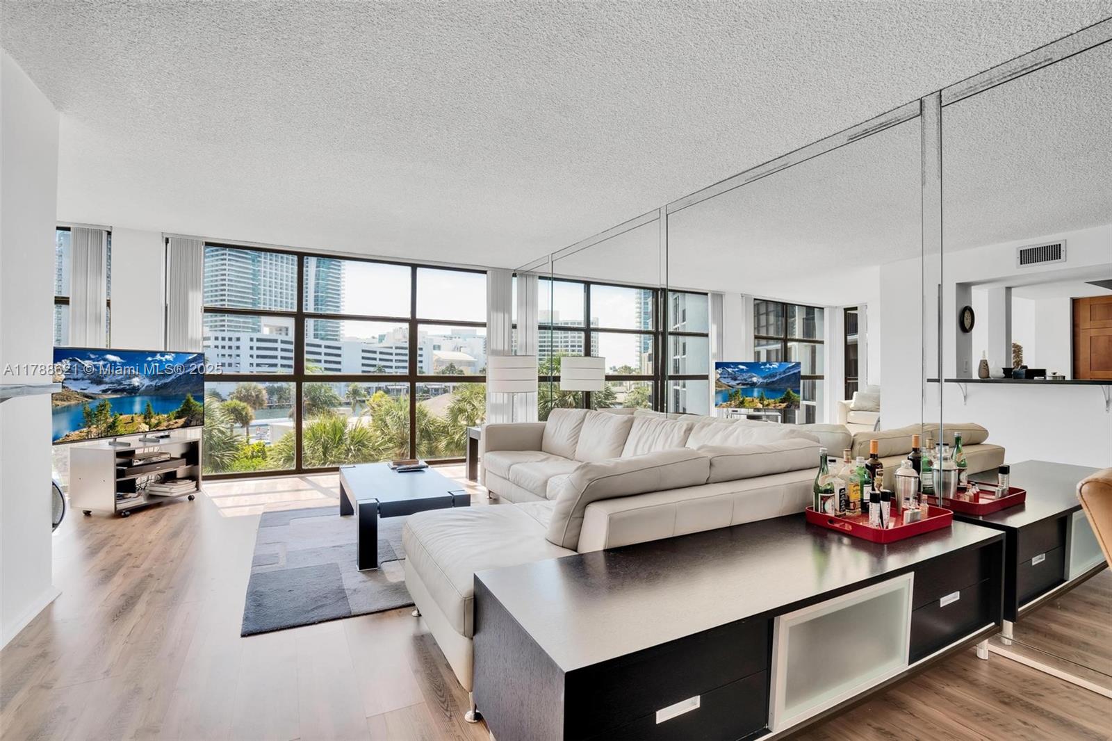 A living room features a white sectional sofa, a black coffee table, and mirrored walls — 600 Parkview Dr, Hallandale Beach FL 33009, HALLANDALE BEACH, FL