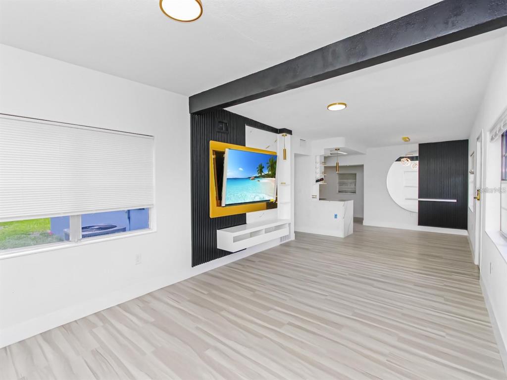 A living room features light wood-look flooring, a black accent wall, and a wall-mounted television — 4201 PARK LAKE STREET, ORLANDO, FL
