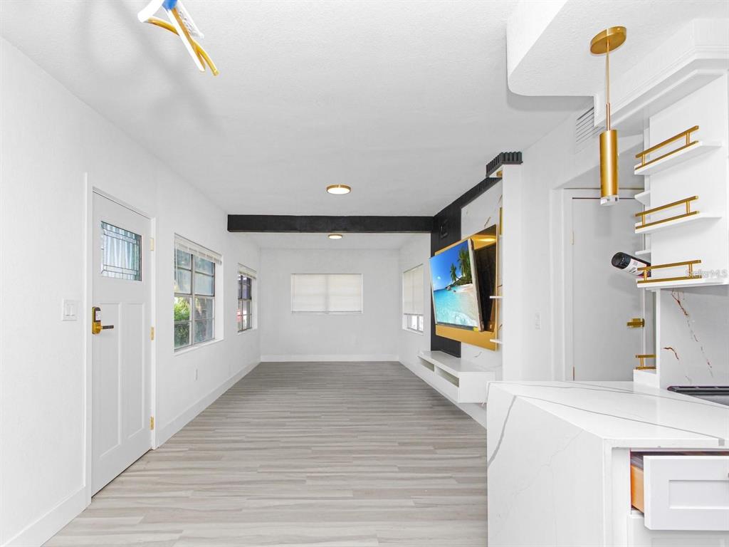 A bright living room features white walls, light wood-look flooring, and a wall-mounted television — 4201 PARK LAKE STREET, ORLANDO, FL