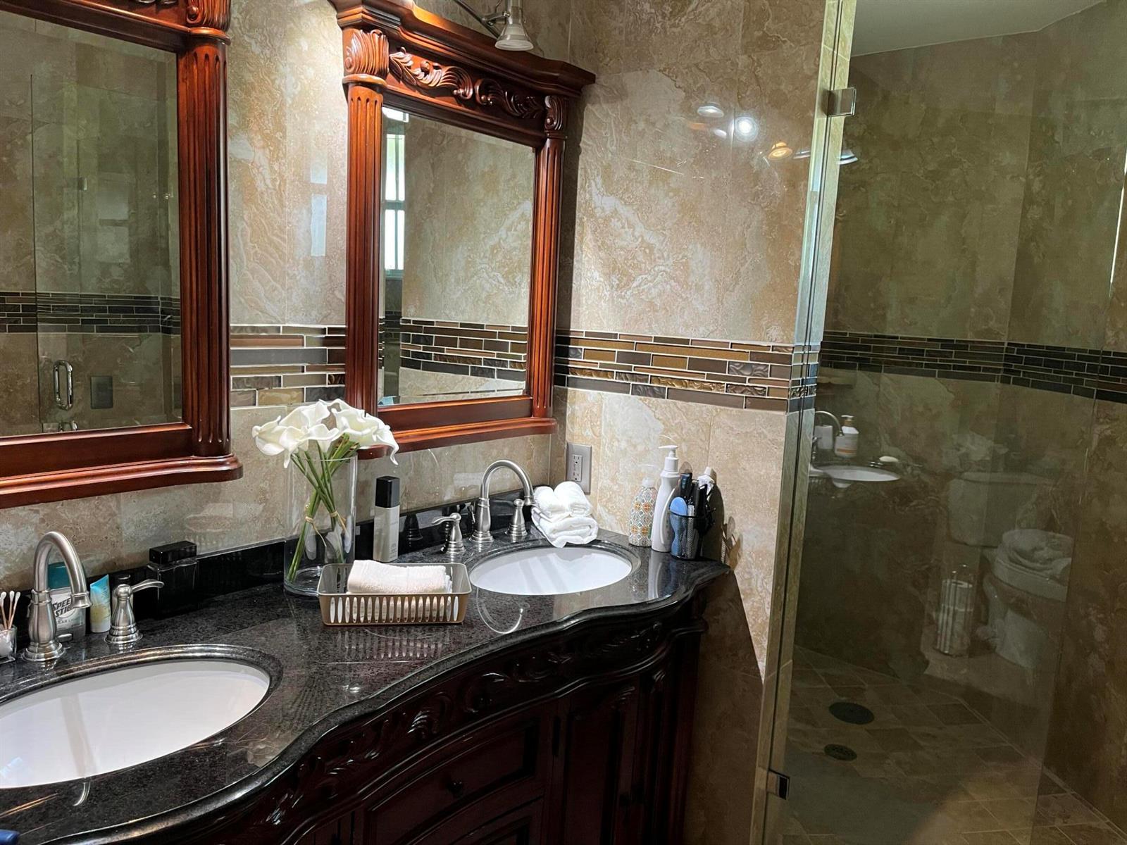 A bathroom features a double vanity with dark wood cabinets, granite countertops, and tiled walls — 6549 Via Regina # 6549, Boca Raton FL 33433, BOCA RATON, FL