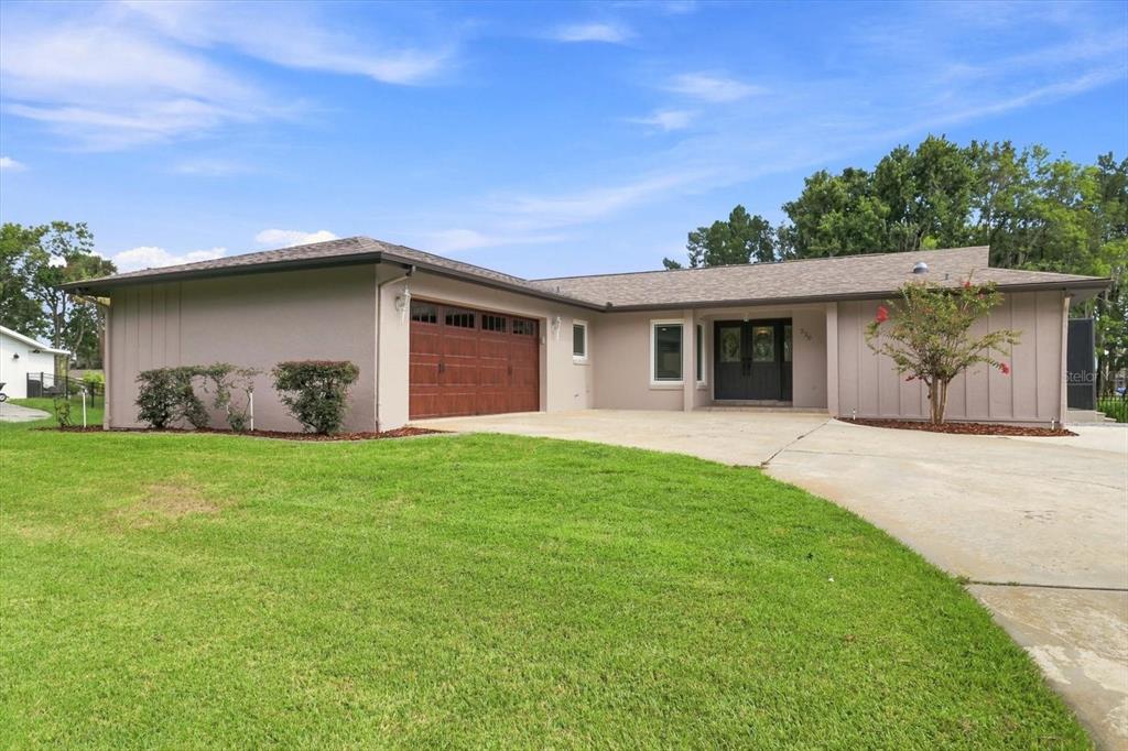 A single-story house with a brown garage door, dark front doors, and a concrete driveway — 220 SE KINGS BAY DRIVE, CRYSTAL RIVER, FL