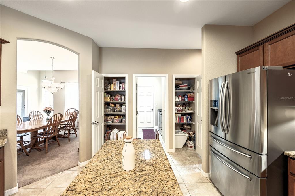 A kitchen with a granite island, stainless steel refrigerator, and two open pantry closets — 2836 WHITNEY STREET, LAKELAND, FL