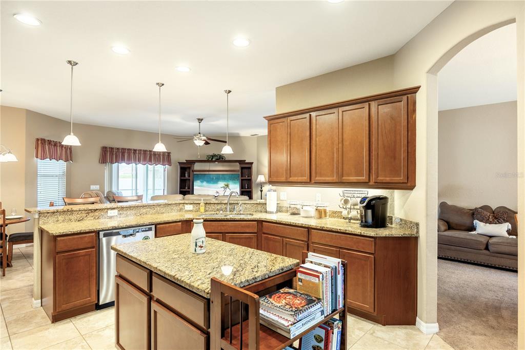 A kitchen with granite countertops, wooden cabinets, and a central island faces a living area — 2836 WHITNEY STREET, LAKELAND, FL