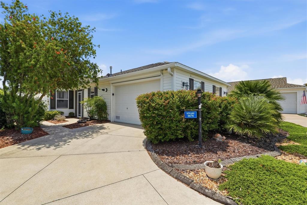 A single-story house with white siding, a garage, and a landscaped front yard — 1674 GOVAN PLACE, THE VILLAGES, FL