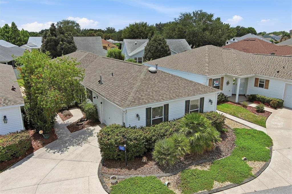 An aerial view shows the exterior of a white house with a shingled roof — 1674 GOVAN PLACE, THE VILLAGES, FL