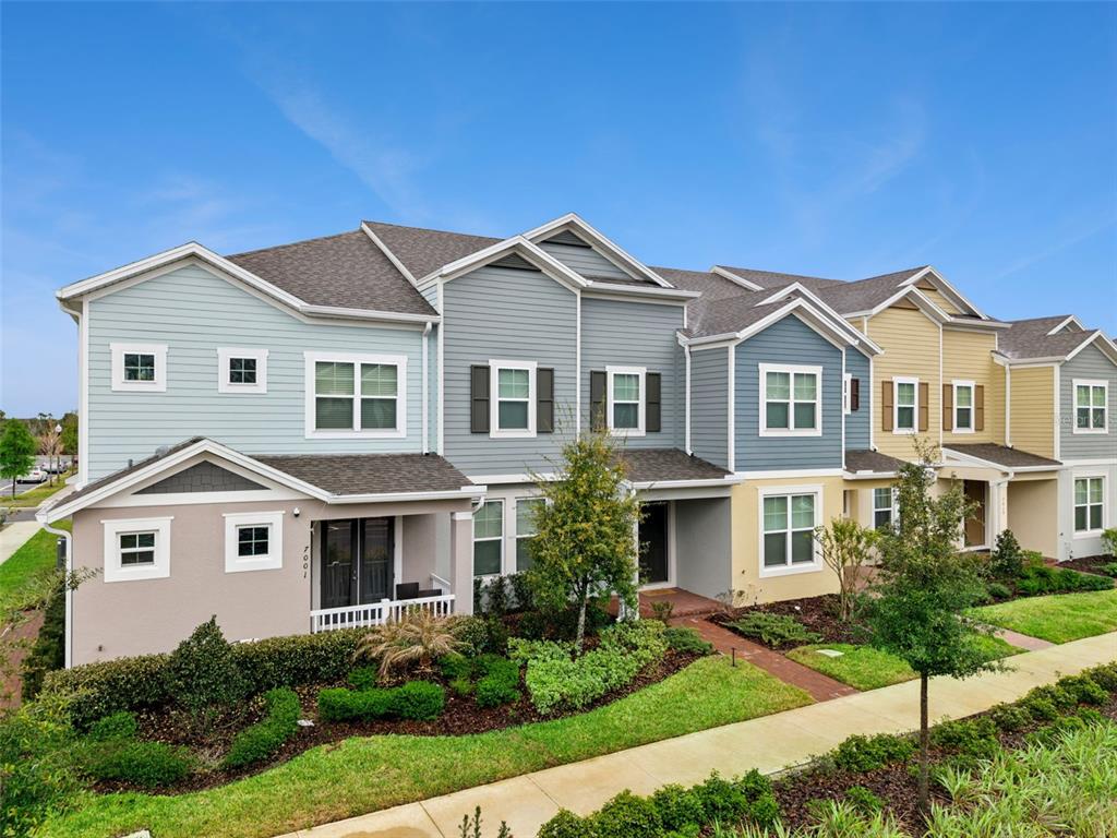 A row of multi-story townhomes with colorful siding and a landscaped front yard — 7007 TWILIGHT BAY DRIVE, WINTER GARDEN, FL