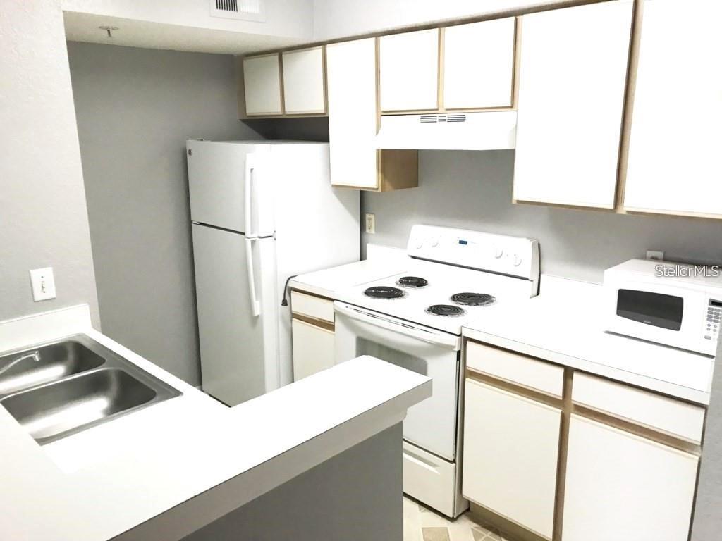 A kitchen features white cabinets, white appliances, a double sink, and a white countertop — 2209 ANTIGUA PLACE UNIT 827, KISSIMMEE, FL