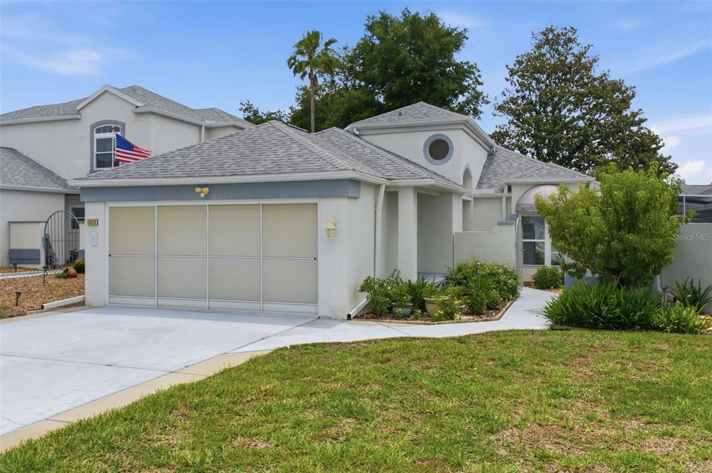 A single-story house with a two-car garage, light-colored stucco exterior, and a gray shingled roof — 10428 CASA GRANDE CIRCLE, SPRING HILL, FL