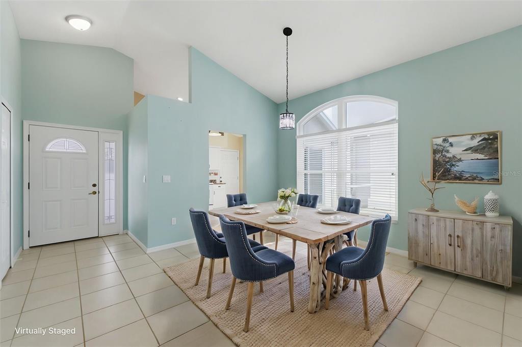 A dining room with light blue walls, tile flooring, a wooden table, and blue chairs — 10428 CASA GRANDE CIRCLE, SPRING HILL, FL