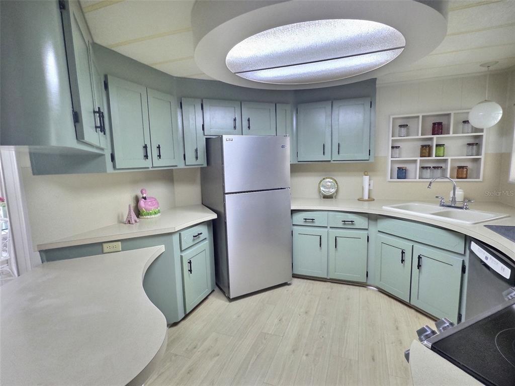 A kitchen features light green cabinets, stainless steel appliances, and a circular recessed ceiling light — 46 PALM FOREST DRIVE, LARGO, FL