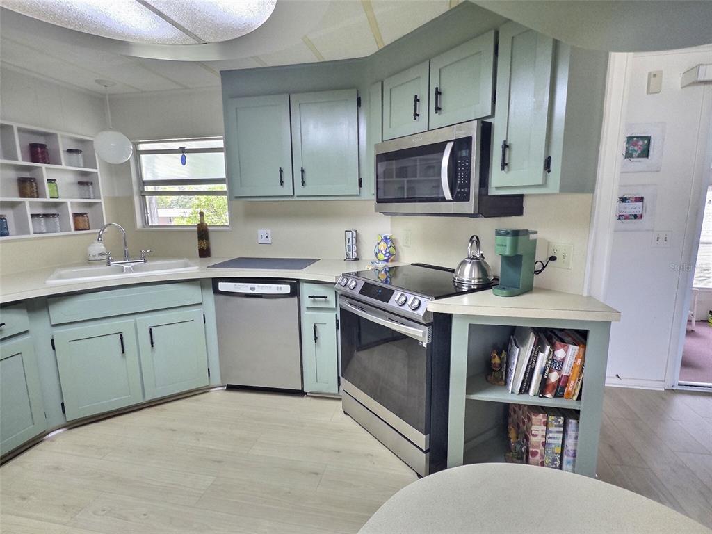 A kitchen features light green cabinets, stainless steel appliances, and a white countertop — 46 PALM FOREST DRIVE, LARGO, FL