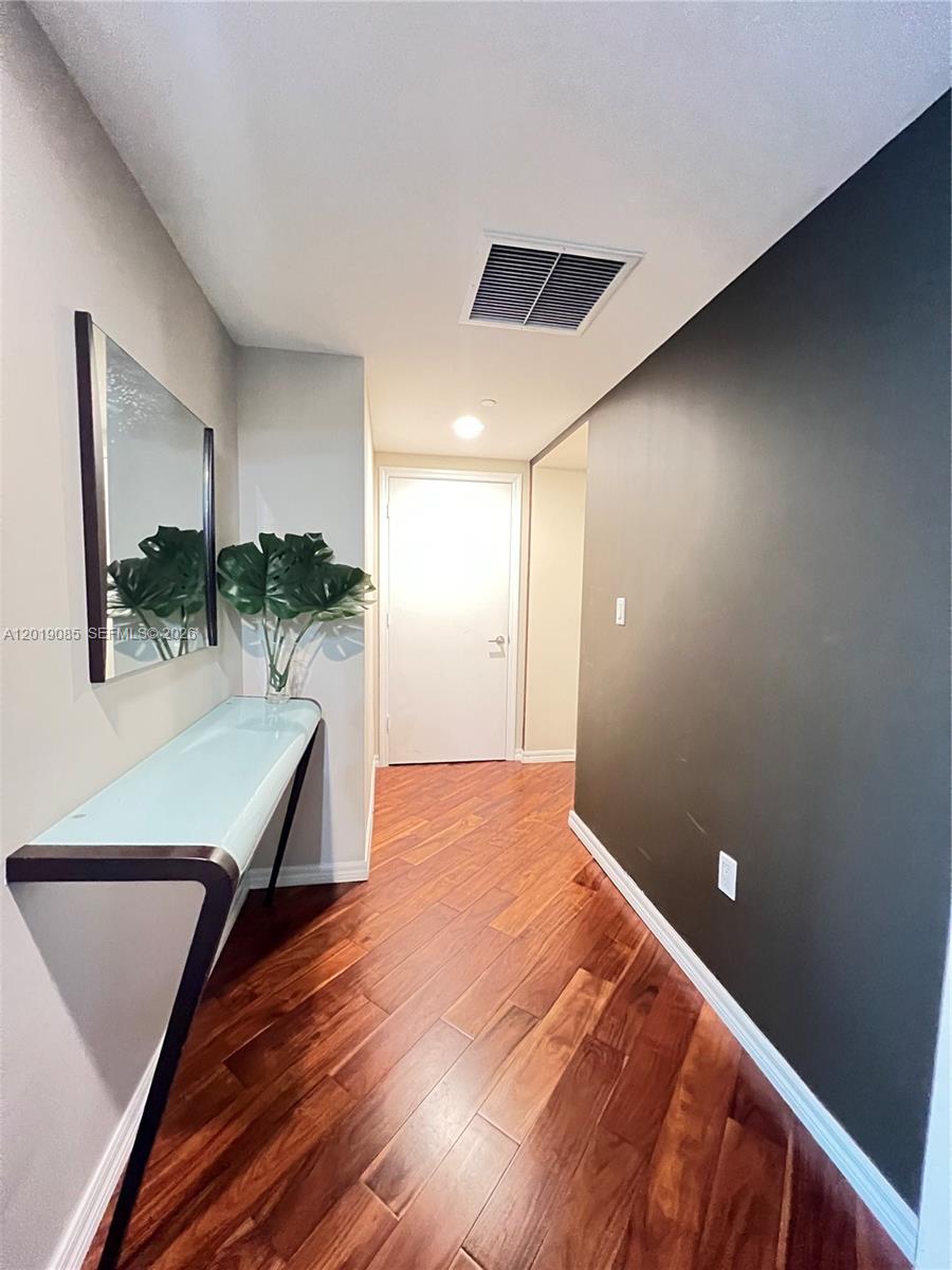 A hallway features dark wood flooring, a glass console table, a mirror, and a dark accent wall — 55 SE 6th St # 3305, Miami FL 33131, MIAMI, FL