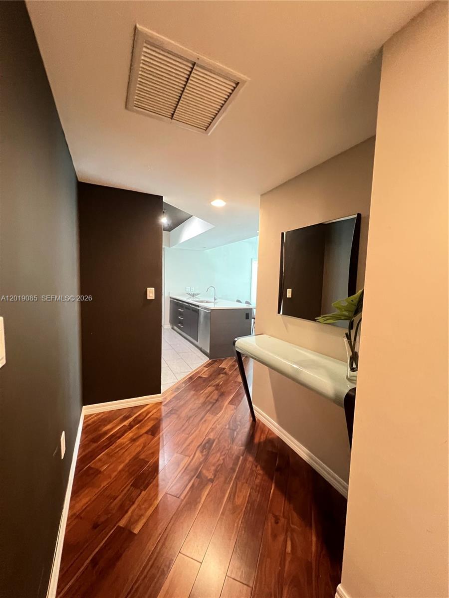 A hallway with dark wood flooring leads toward a kitchen with a central island — 55 SE 6th St # 3305, Miami FL 33131, MIAMI, FL