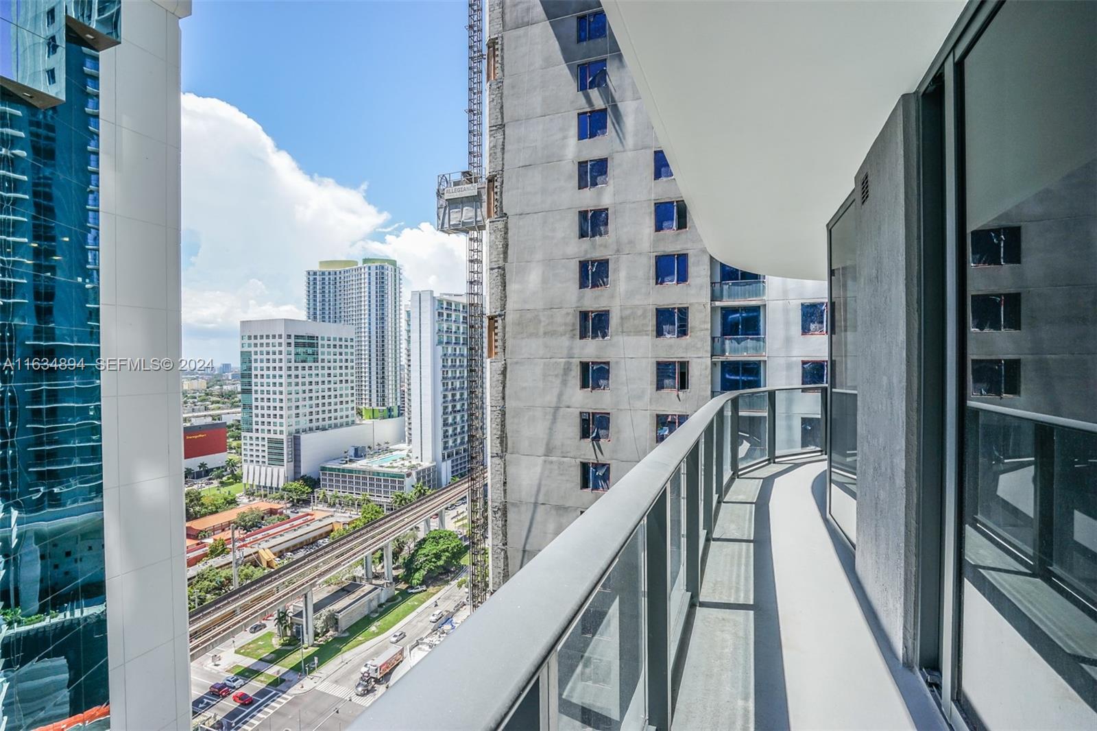 A curved balcony overlooks a city street, train tracks, and neighboring high-rise buildings — 55 SW 9th ST # 2108, Miami FL 33130, MIAMI, FL