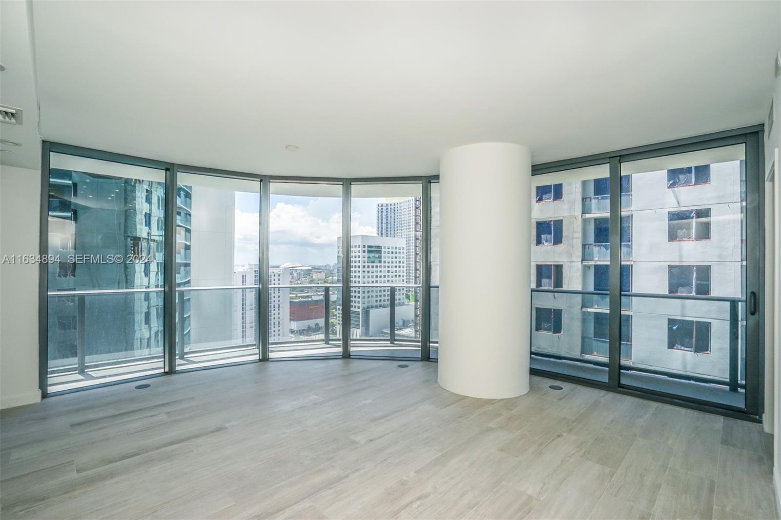 An empty room features light wood-look flooring, floor-to-ceiling windows, and a central white column — 55 SW 9th ST # 2108, Miami FL 33130, MIAMI, FL