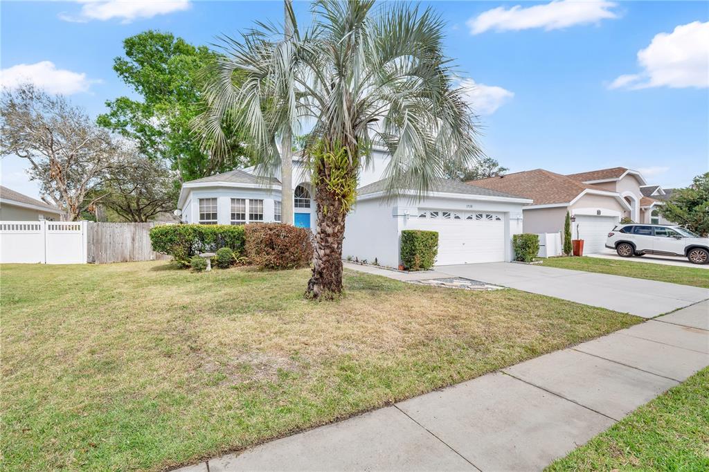 A single-story house with a white exterior, a two-car garage, and a large palm tree — 13538 FORDWELL DRIVE, ORLANDO, FL