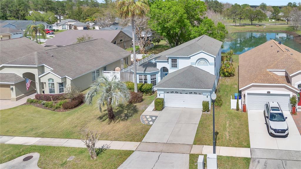 An aerial view shows a two-story suburban house with a garage and a nearby pond — 13538 FORDWELL DRIVE, ORLANDO, FL