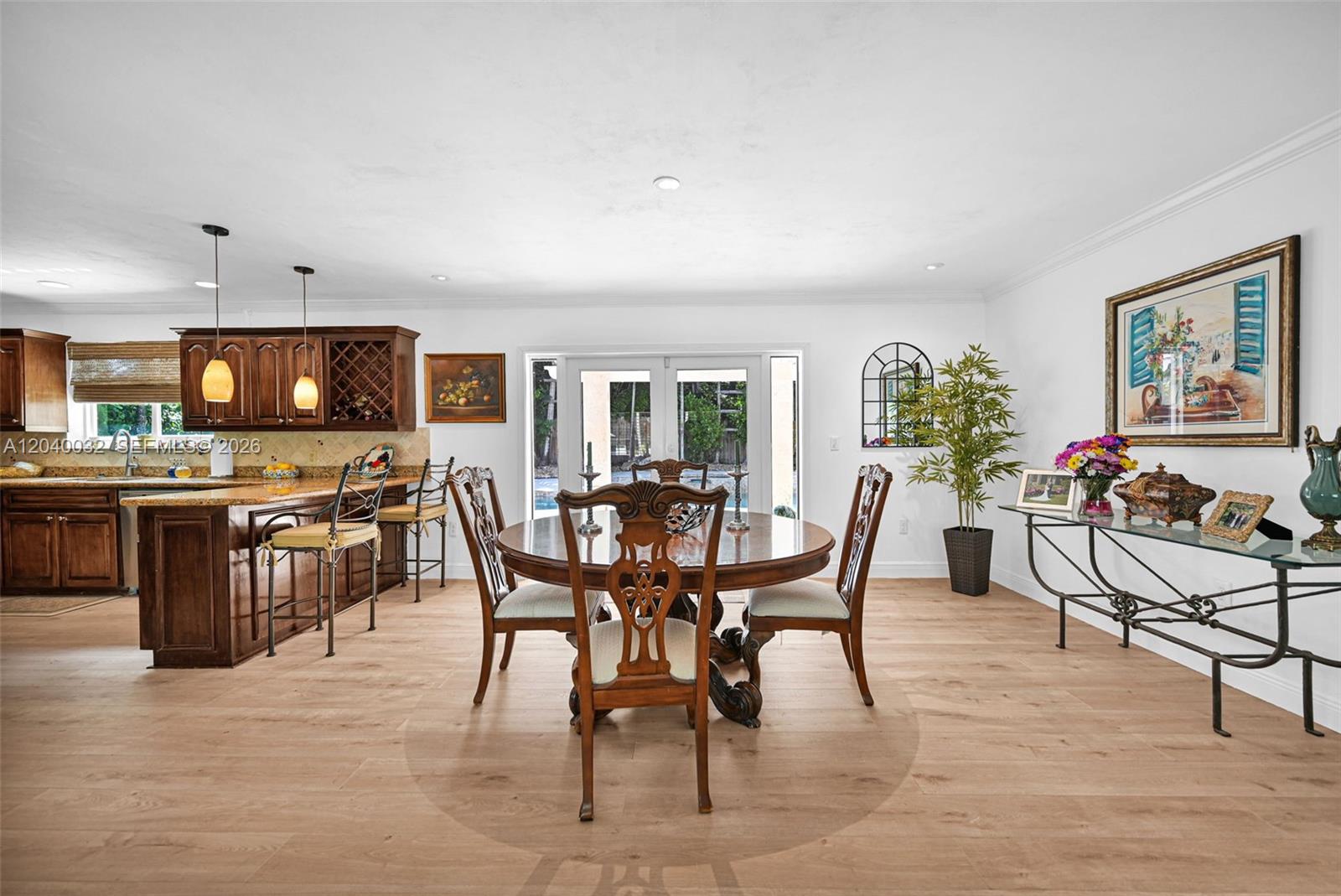 A dining area with a round wooden table sits adjacent to a kitchen with cabinets — 14501 SW 99th Ave, Miami FL 33176, MIAMI, FL