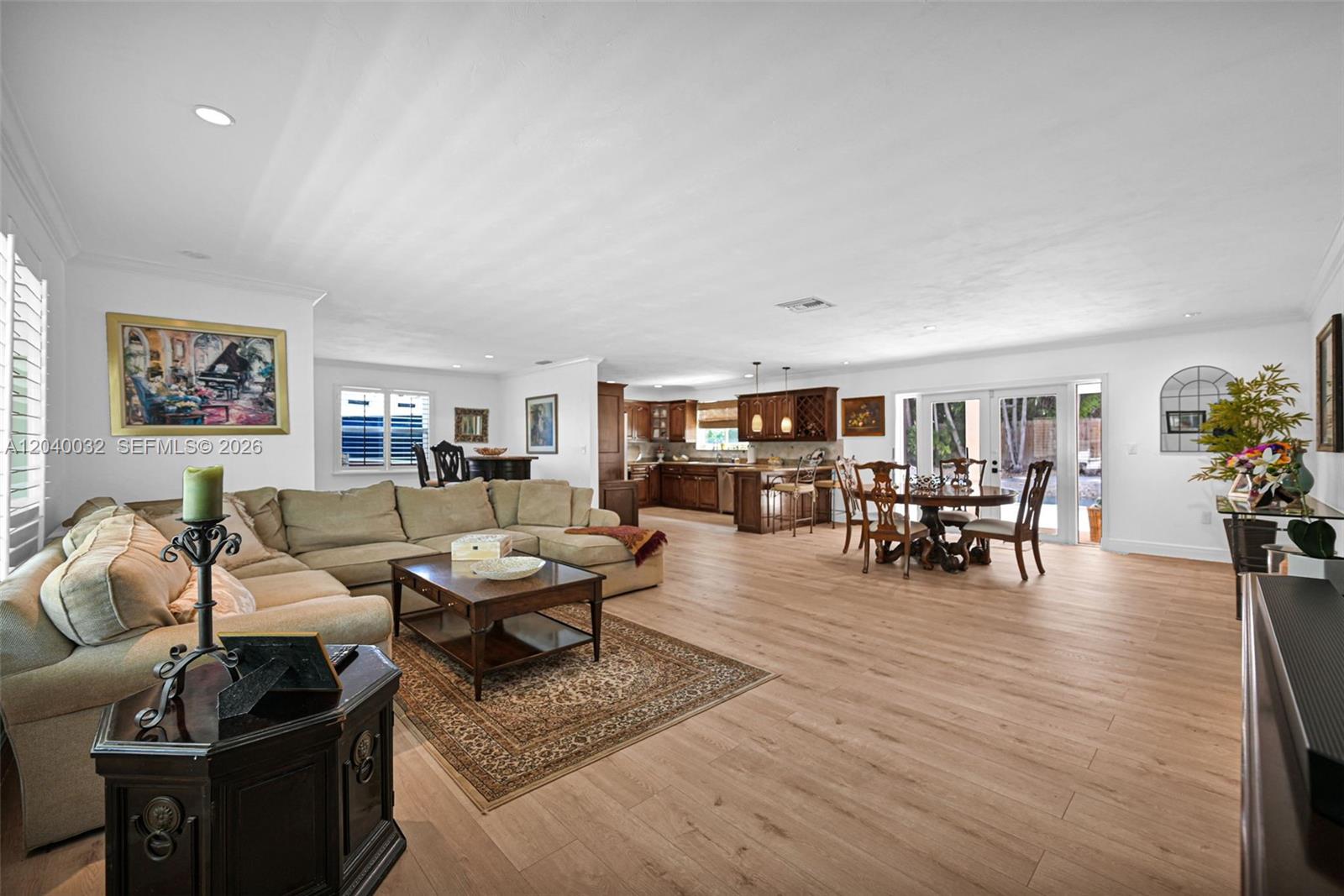 An open-concept living area features a sectional sofa, dining set, and kitchen with wood cabinetry — 14501 SW 99th Ave, Miami FL 33176, MIAMI, FL