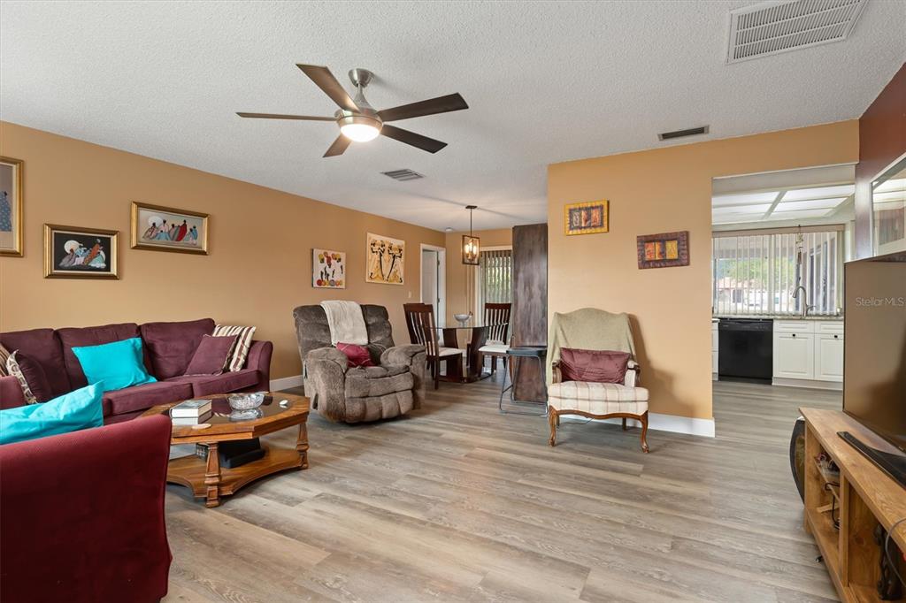 A living room with wood-look flooring, a ceiling fan, and an adjacent dining area — 23226 MIDWAY BOULEVARD, PUNTA GORDA, FL